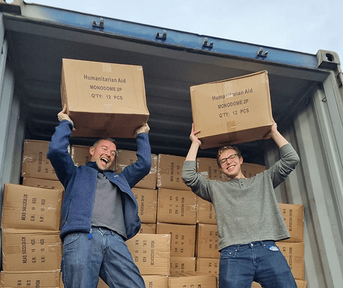 two volunteers holding boxes of aid supplies